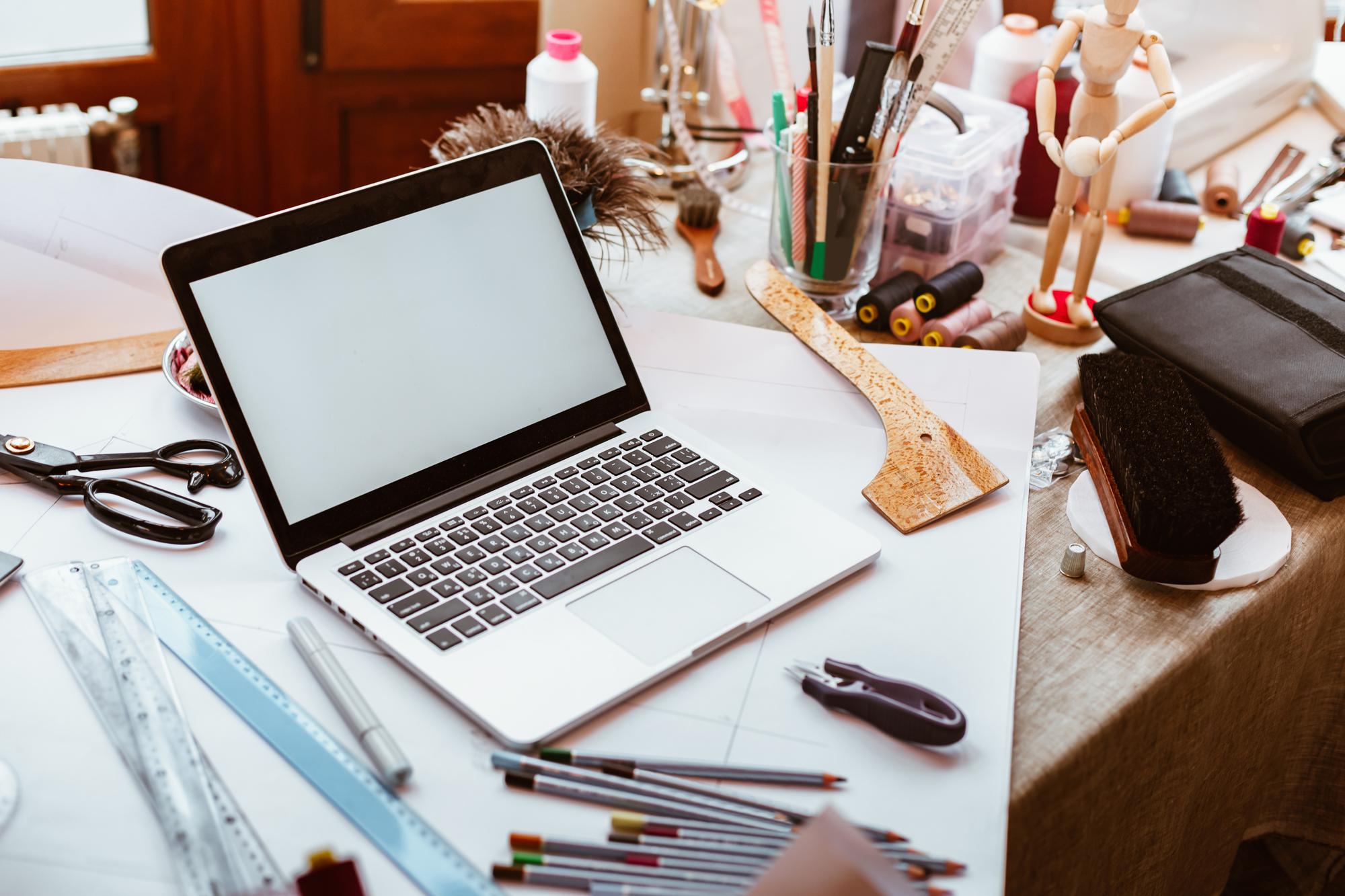 Workspace with laptop and embroidery sketches
